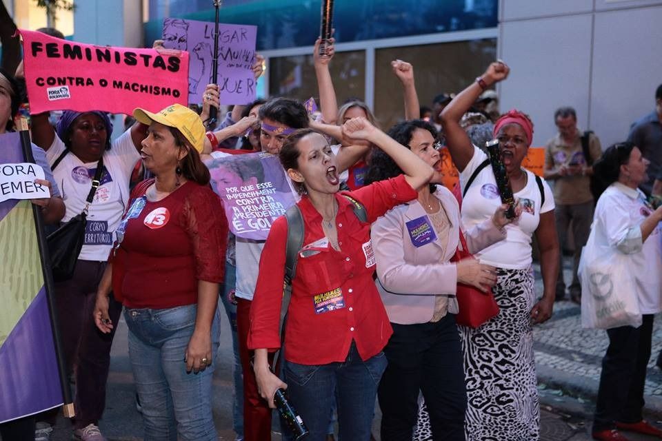 Cristiane Patinho, de camisa vermelha e com punho erguido, participando de um protesto feminista no Rio de Janeiro.